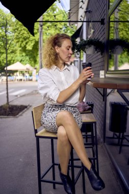 70 'li yaşlarda, 80' li yaşlarda güzel bir kadın modern bir kafede oturup kahve içiyor.              