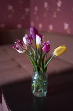 İç kısımda şeffaf bir kavanozda bir buket çok renkli lale.