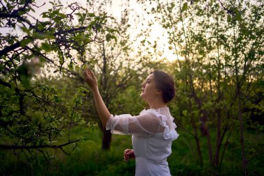 Bahar bahçesinde gün batımında trenle beyaz bir elbise içinde güzel bir kadın.