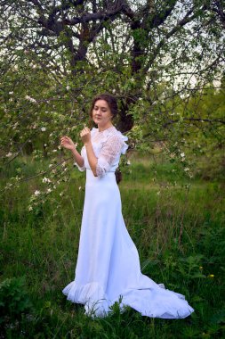 Bahar bahçesinde gün batımında trenle beyaz bir elbise içinde güzel bir kadın.