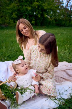 Anne büyük kızın saçını tarar, büyük kız da küçük kızın saçını tarar.