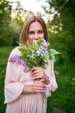 Bir buket leylakla güzel bir genç kadının portresi.