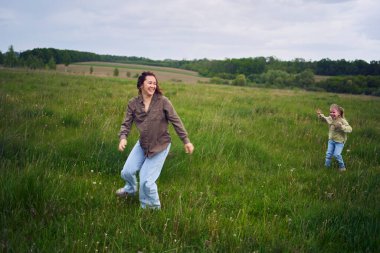 Bir anne kızlarıyla kovalamaca oynar.