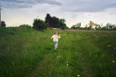        İki kız kardeş tarlada uçurtma tamir edip uçuruyorlar.                        