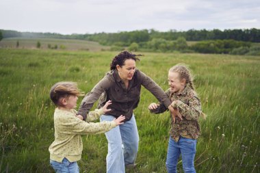 a mother breaks up the children who are fighting in the rain in the field clipart