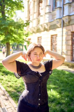  Orta boylu, siyah korseli ve geniş paçalı bir kadın sabah vakti şehirde yürür.                            