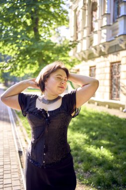  Orta boylu, siyah korseli ve geniş paçalı bir kadın sabah vakti şehirde yürür.                            
