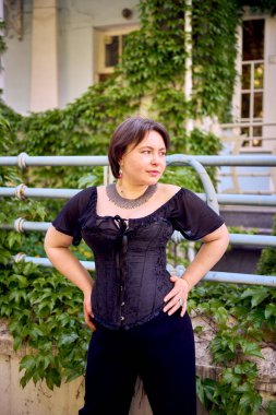  Orta boylu, siyah korseli ve geniş paçalı bir kadın sabah vakti şehirde yürür.                            