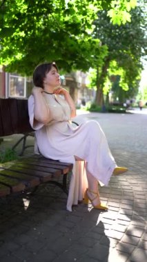 Artı şeftali tüylü elbiseli bir kadın sabah şehirde yürüyor.