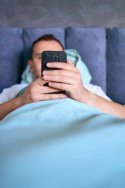 Genç adam sabah uyandıktan sonra akıllı telefondan kayar, sabah rutini.