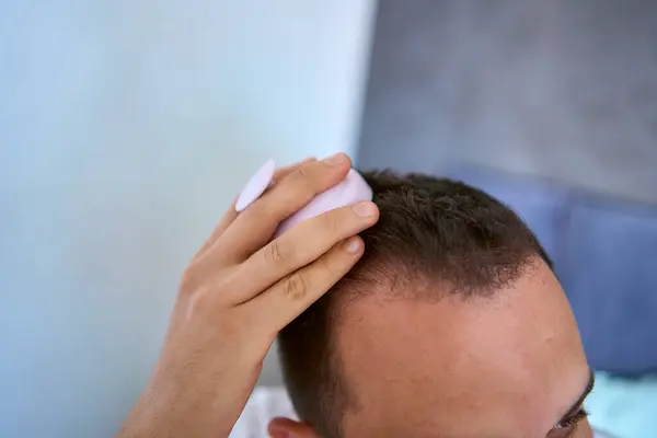  Bir adam saçlarını uzatmak için kafasına masaj yapıyor.