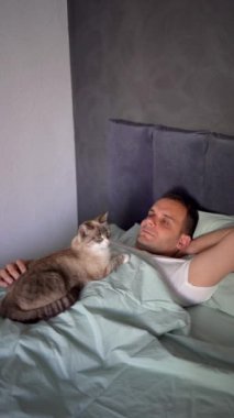 Genç adam göğsünde bir kediyle uyuyor, sabah rutini.
