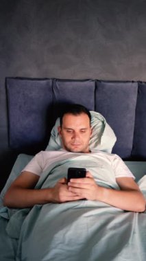 Genç adam sabah uyandıktan sonra akıllı telefondan kayar, sabah rutini.