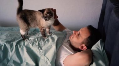 Genç adam göğsünde bir kediyle uyuyor, sabah rutini.