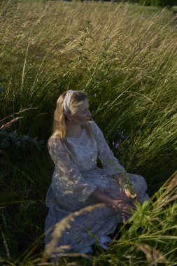 Pastel şifon giysili genç sarışın bir kadının portresi.