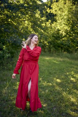 Parktaki kırmızı elbiseli, uzun sarı saçlı, 30 yaşında güzel bir kadının portresi.