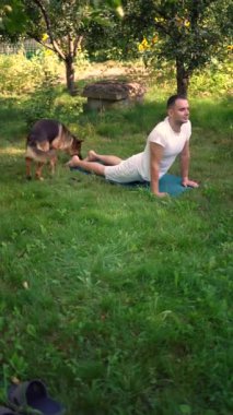 Bir adam sabah köpeğiyle bahçede somatik egzersizler yapar.