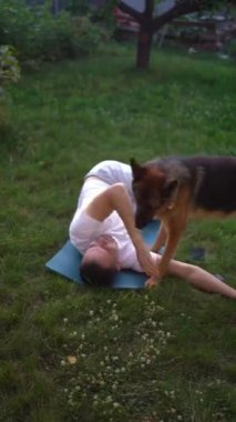 Bir adam sabah köpeğiyle bahçede somatik egzersizler yapar.