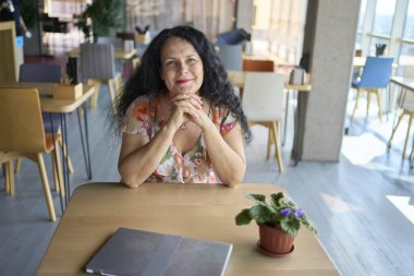 57 yaşındaki bir kadın, modern bir ofis çalışma alanında dizüstü bilgisayarda çalışıyor.                    