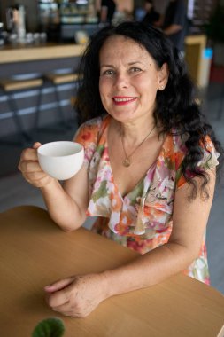      60 'lı yılların kadını öğle arasında modern iş yerinde ısırgan otu çayı içiyor.                       