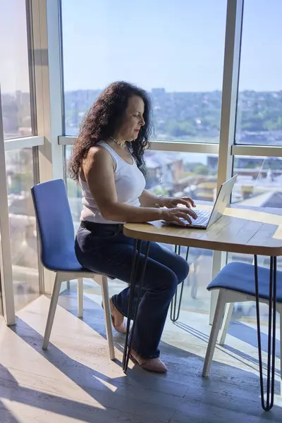 stock image 57-year-old woman works on a laptop in a modern office workspace