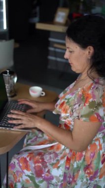57 yaşında bir kadın, modern bir ofis çalışma alanında dizüstü bilgisayarda çalışıyor.