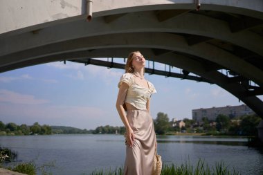 İpek etekli güzel bir genç kız ve eski para tarzında bir korse. Moda fotoshoot köprünün altında.