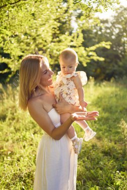  Anne, kızıyla güneşli bir bahçede oynuyor.