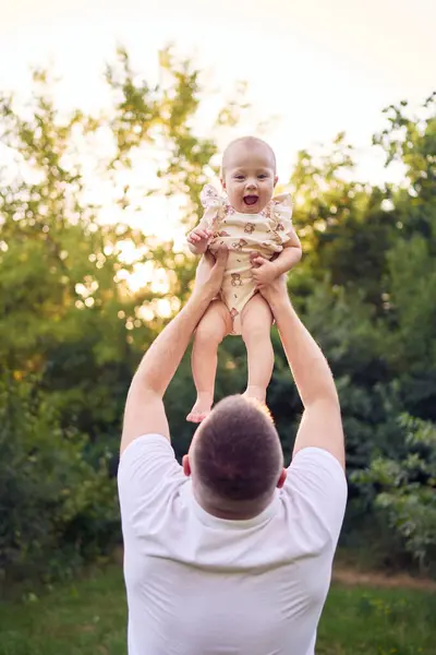 stock image          dad playing with his baby daughter in a garden                      