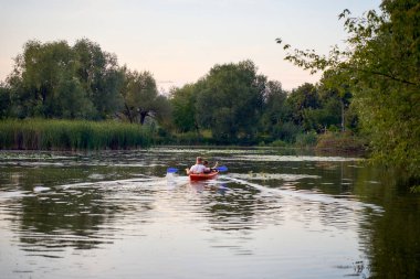     Birbirlerine aşık çiftler gün batımında nehirde kano yapıyorlar.                           
