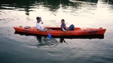 Birbirlerine aşık çiftler gün batımında nehirde kano yapıyorlar.