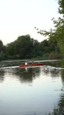 Birbirlerine aşık çiftler gün batımında nehirde kano yapıyorlar.