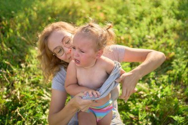 Bir anne yeni yürümeye başlayan bir çocuğu giydirir. Bağırır, giyinmekten nefret eder.                          
