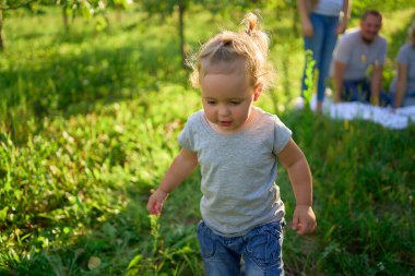      Küçük çocuk bahçede piknikte ailenin önünde bağırır ve ağlar.                          
