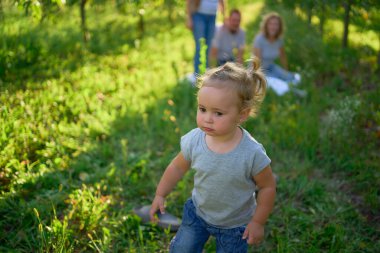      Küçük çocuk bahçede piknikte ailenin önünde bağırır ve ağlar.                          
