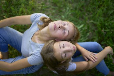                Uzun sarı saçlı anne ve genç kızlar güneşli parkta birlikte vakit geçiriyorlar.             