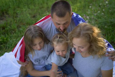 Bağımsızlık Günü pikniğinde Amerikan bayrağıyla bir aile                  