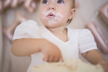 Küçük kız ilk doğum günü pastasını annesi ve küçük kız kardeşiyle denedi.