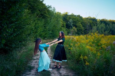 Yazın gün batımında bir tarlada Alman bir çobanla garip bir estetik elbise giymiş iki kadın.