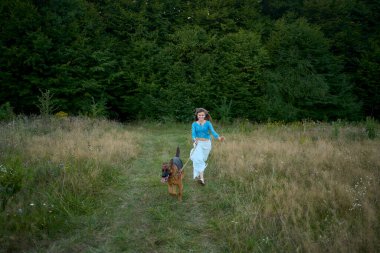  Tarlada Alman çoban köpeği olan tuhaf estetik elbiseli bir kadın.