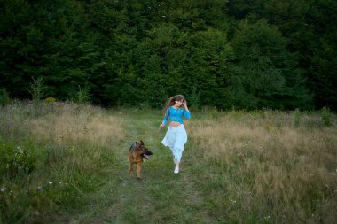  Tarlada Alman çoban köpeği olan tuhaf estetik elbiseli bir kadın.