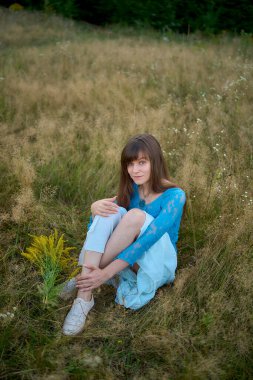         Yazın gün batımında sahada estetik tarzda giyinmiş bir kadın.                       