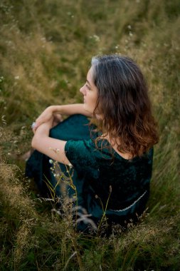         Yazın gün batımında sahada estetik tarzda giyinmiş bir kadın.                       