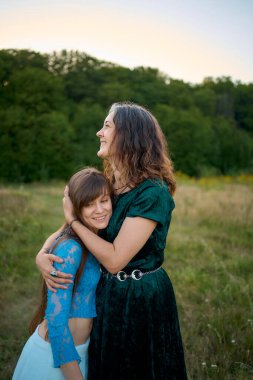 Yazın gün batımında bir tarlada tuhaf bir estetik elbise giymiş iki kadın.