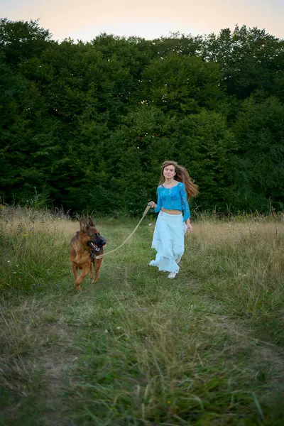 Stock image  woman in a Whimsical Aesthetic style dress with a German shepherd in a field