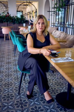               Orta yaşlı ve zengin bir kadın şık bir restoranda eski moda kıyafetler giyiyor.                                                 