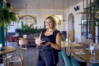               Orta yaşlı ve zengin bir kadın şık bir restoranda eski moda kıyafetler giyiyor.                                                 