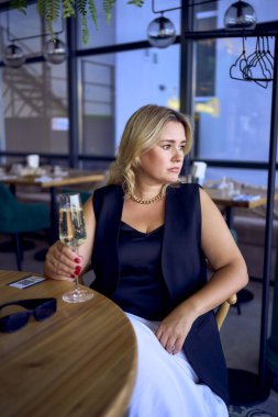 a middle-aged plus size woman in old money style clothes drinking sparkling wine in a fancy restaurant                      clipart