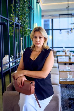        Orta yaşlı ve zengin bir kadın şık bir restoranda eski moda kıyafetler giyiyor.                         