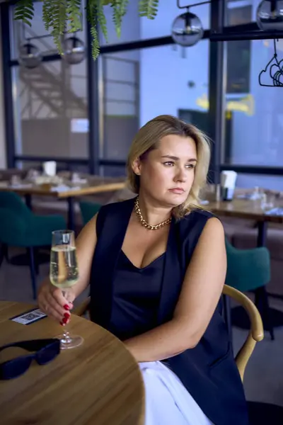 stock image a middle-aged plus size woman in old money style clothes drinking sparkling wine in a fancy restaurant                     